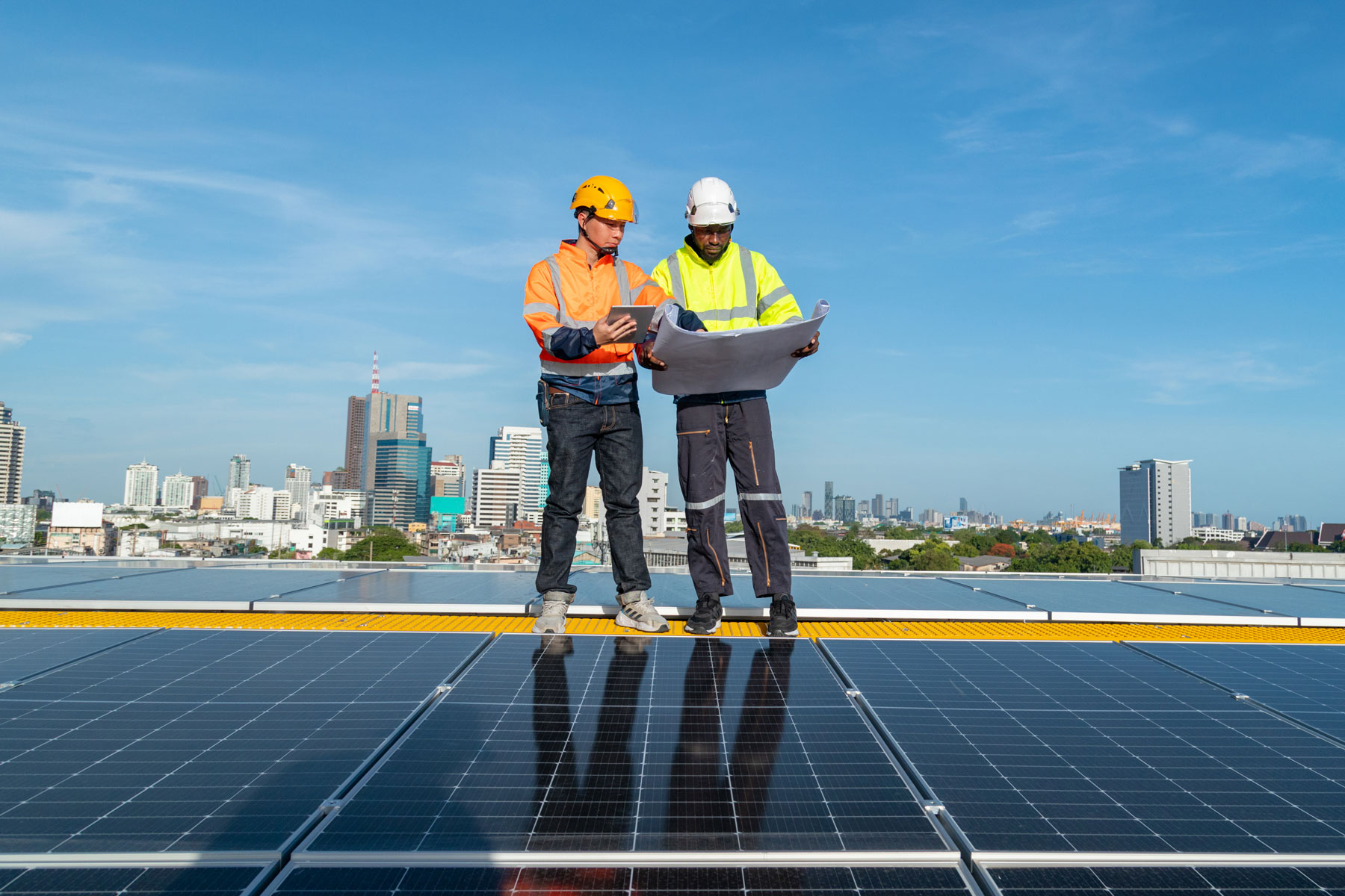 Two people in high vis clothing standing on solar panels
