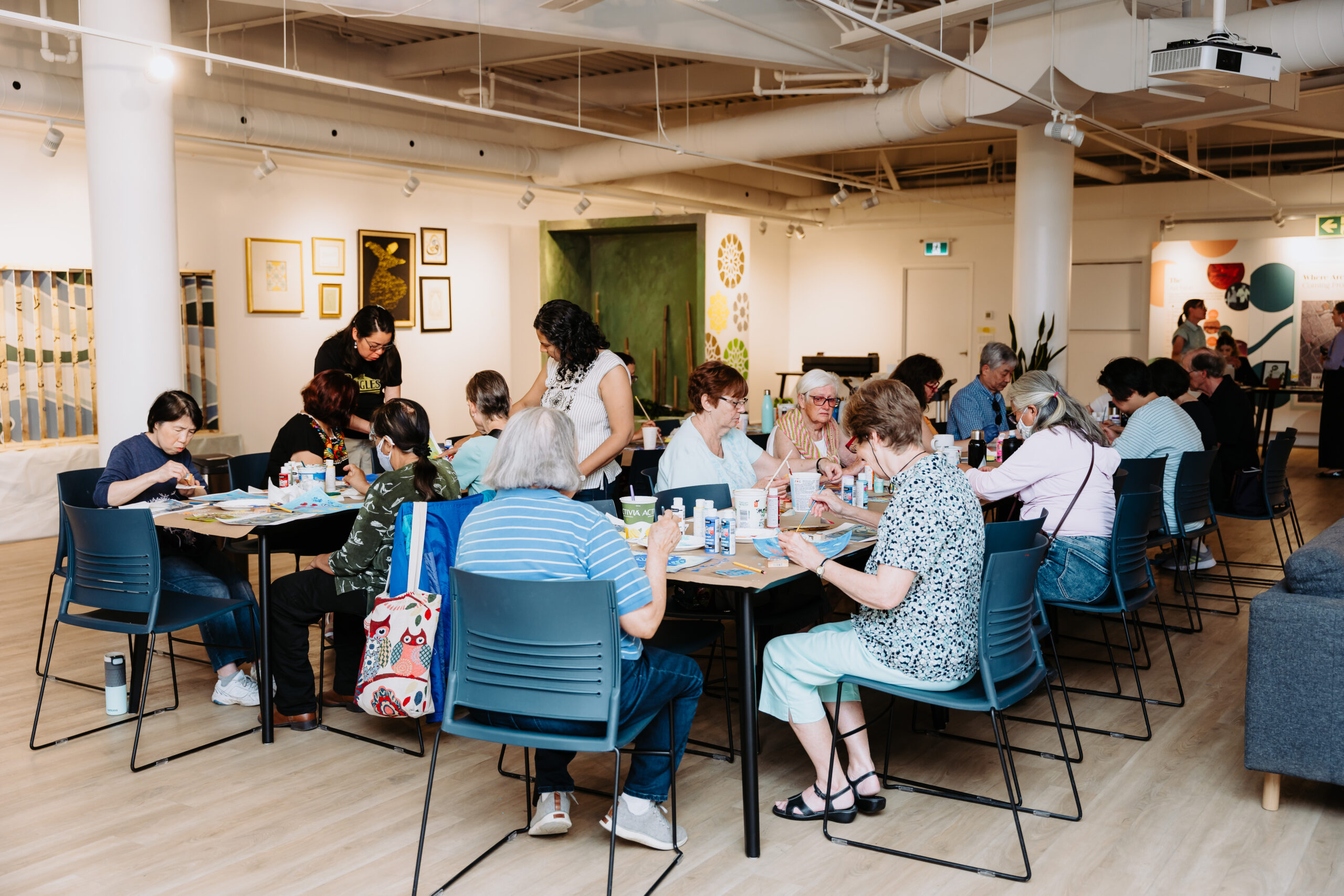 A group of people sitting around tables, creating art.